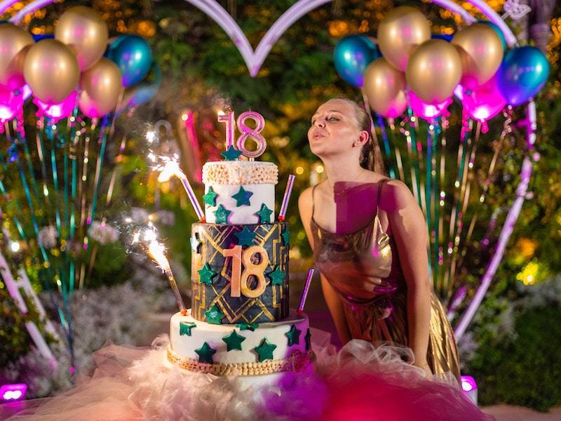 18th birthday celebration with three-tiered cake, sparklers, and balloons in a garden.